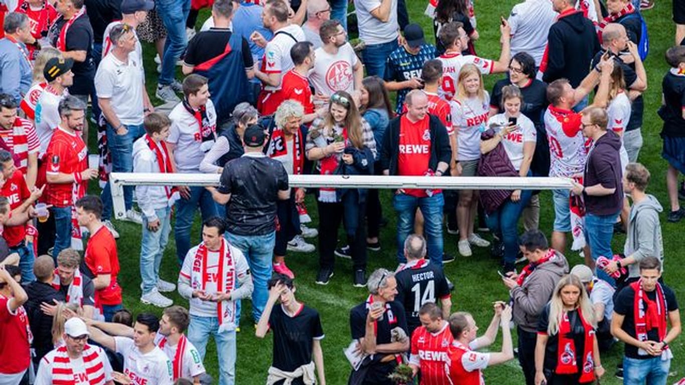 Kölner Fans halten nach einem Platzsturm einen Torpfosten.