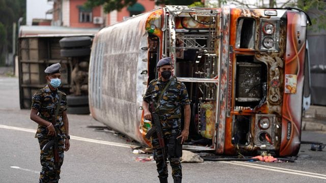 Soldaten stehen in Colombo vor einem ausgebrannten verbranntem Bus Wache, nachdem es zu Zusammenstößen zwischen Regierungsanhängern und -gegnern kam.