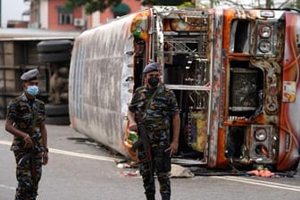 Soldaten stehen in Colombo vor einem ausgebrannten verbranntem Bus Wache, nachdem es zu Zusammenstößen zwischen Regierungsanhängern und -gegnern kam.