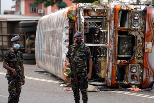 Soldaten stehen in Colombo vor einem ausgebrannten verbranntem Bus Wache, nachdem es zu Zusammenstößen zwischen Regierungsanhängern und -gegnern kam.