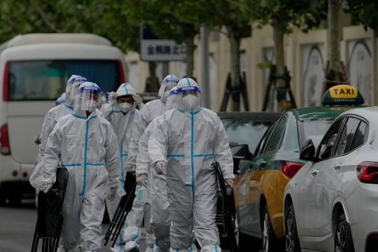 Arbeiter des Gesundheitswesens sind auf dem Weg zu einem abgesperrten Wohnkomplex in Peking.