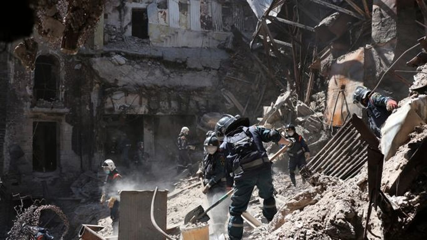 Mitarbeiter des Ministeriums für Notsituationen der selbst ernannten Volksrepublik Donezk räumen Trümmer an der Seite des schwer beschädigten Theatergebäudes.