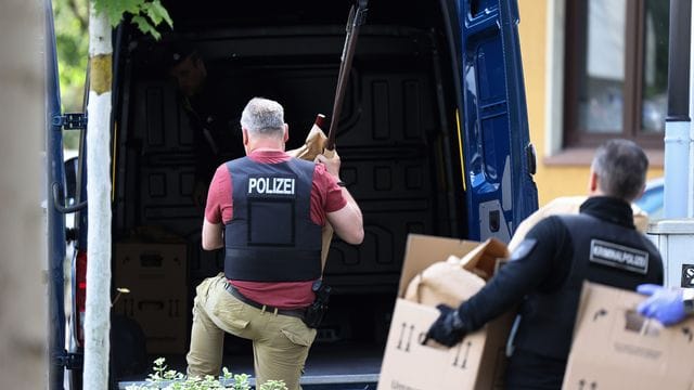 Polizisten tragen Gegenstände, darunter mehrere Stichwaffen und Speere, aus dem Wohnhaus des Verdächtigen. Polizisten tragen Gegenstände, darunter mehrere Stichwaffen und Speere, aus dem Wohnhaus des Verdächtigen.
