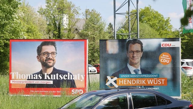 Wahlplakate mit Portraits von Ministerpräsident Hendrik Wüst (r) und Herausforderer Thomas Kutschaty von der SPD.