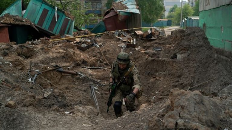 Ein Uniformierter inspiziert einen Krater nach einem Luftangriff der russischen Streitkräfte in der Region Luhansk.