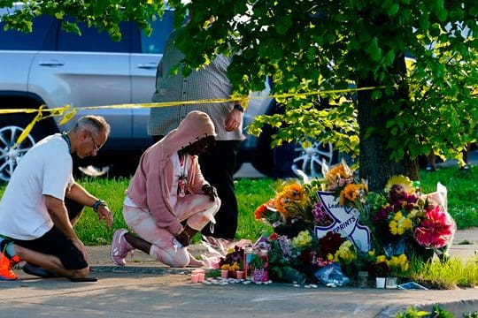 Menschen knien vor Blumen, um den Opfern tödlicher Schüsse in einem Supermarkt in Buffalo die letzte Ehre zu erweisen.