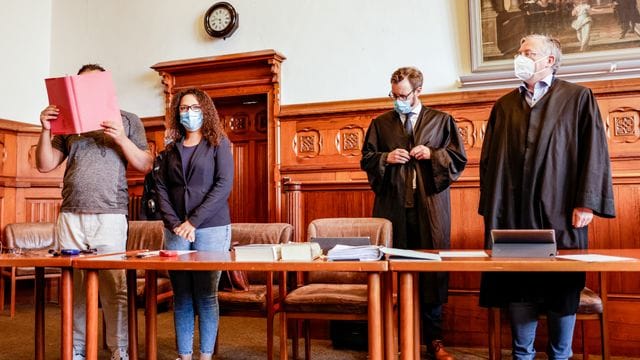 Der 34-jährige Angeklagte (l-r) im Auftakt-Prozess wegen Mordes neben einer Übersetzerin und seinen Anwälten in Flensburg.
