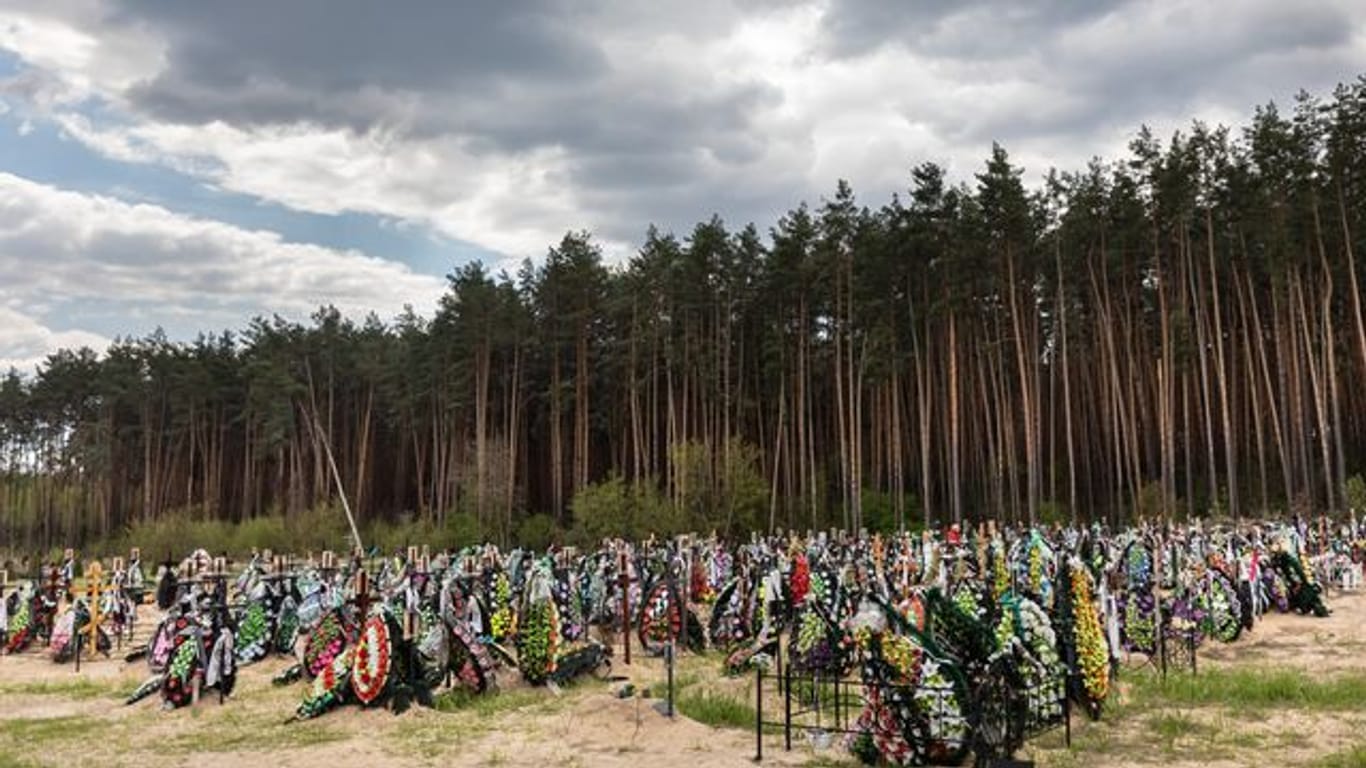 Zahlreiche Blumen und Fotos erinnern an frischen Gräber auf dem Friedhof in Irpin an dort begrabene Einwohner und Mitglieder der Territorialverteidigung, die bei der russischen Invasion in der Ukraine getötet wurden.