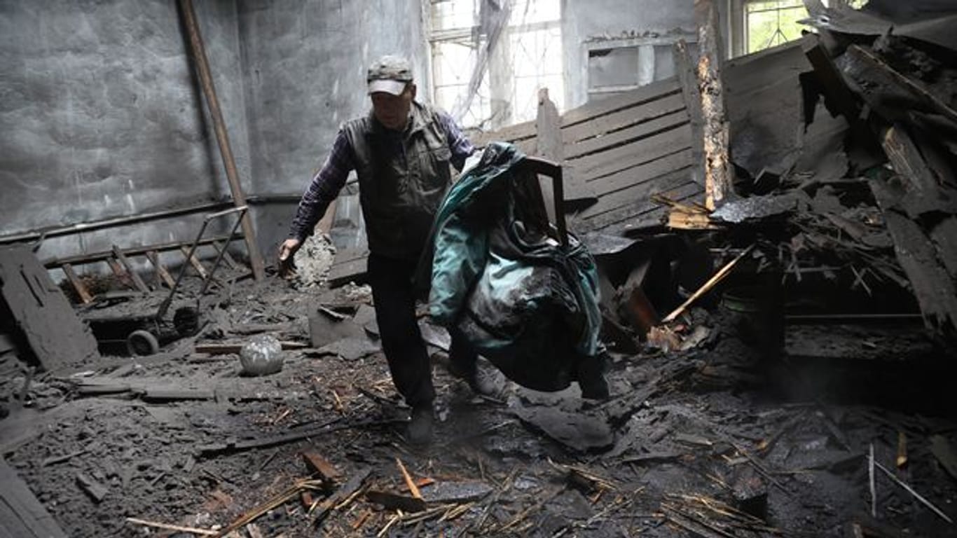 Ein Mann holt Stühle aus einem durch Granatenbeschuss zerstörten Haus.