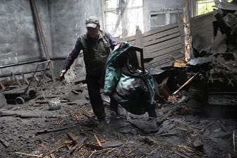 Ein Mann holt Stühle aus einem durch Granatenbeschuss zerstörten Haus.