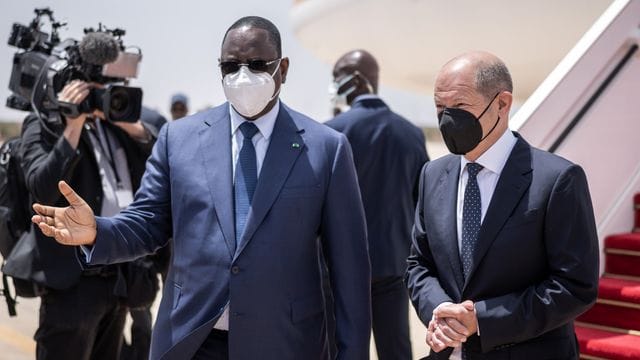 Bundeskanzler Olaf Scholz (r, SPD), wird von Macky Sall, Präsident der Republik Senegal mit militärischen Ehren am Flughafen begrüßt.