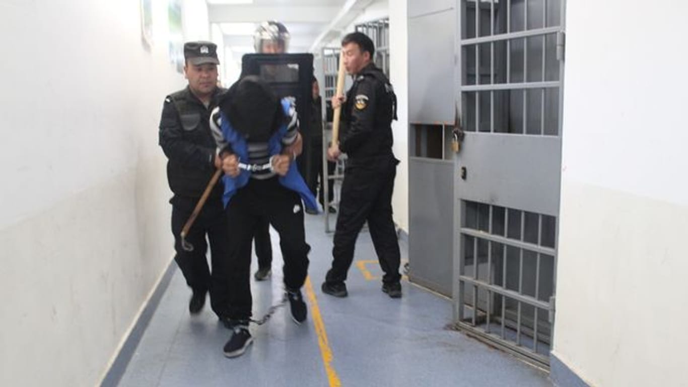 Das Foto aus den Xinjiang Police Files soll Polizisten im Jahr 2018 in einem Umerziehungslager bei einer Festnahme zeigen.