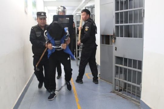 Das Foto aus den Xinjiang Police Files soll Polizisten im Jahr 2018 in einem Umerziehungslager bei einer Festnahme zeigen.