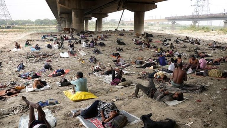 Obdachlose schlafen an einem heißen Tag in Neu-Delhi im Schatten einer Überführung.