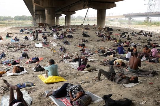 Obdachlose schlafen an einem heißen Tag in Neu-Delhi im Schatten einer Überführung.