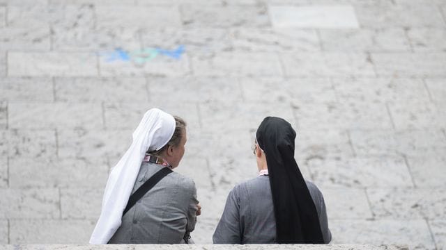 Zwei Besucherinnen des Katholikentags sitzen auf einer Treppe.