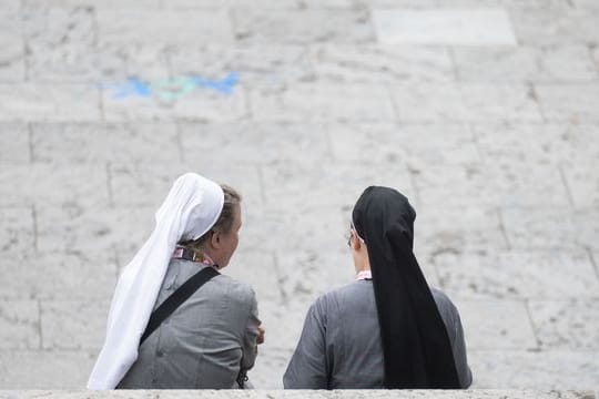 Zwei Besucherinnen des Katholikentags sitzen auf einer Treppe.