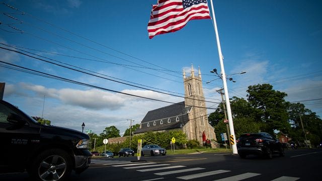 US-Flagge auf halbmast vor einer Kirche, in der eine Mahnwache aus Solidarität mit den Familien von Uvalde stattfindet. US-Flagge auf halbmast vor einer Kirche, in der eine Mahnwache aus Solidarität mit den Familien von Uvalde stattfindet.