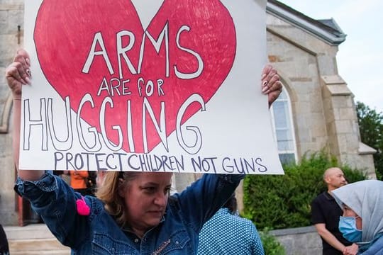 Ein Plakat, das fordert, Kinder zu schützen - und nicht Waffen.