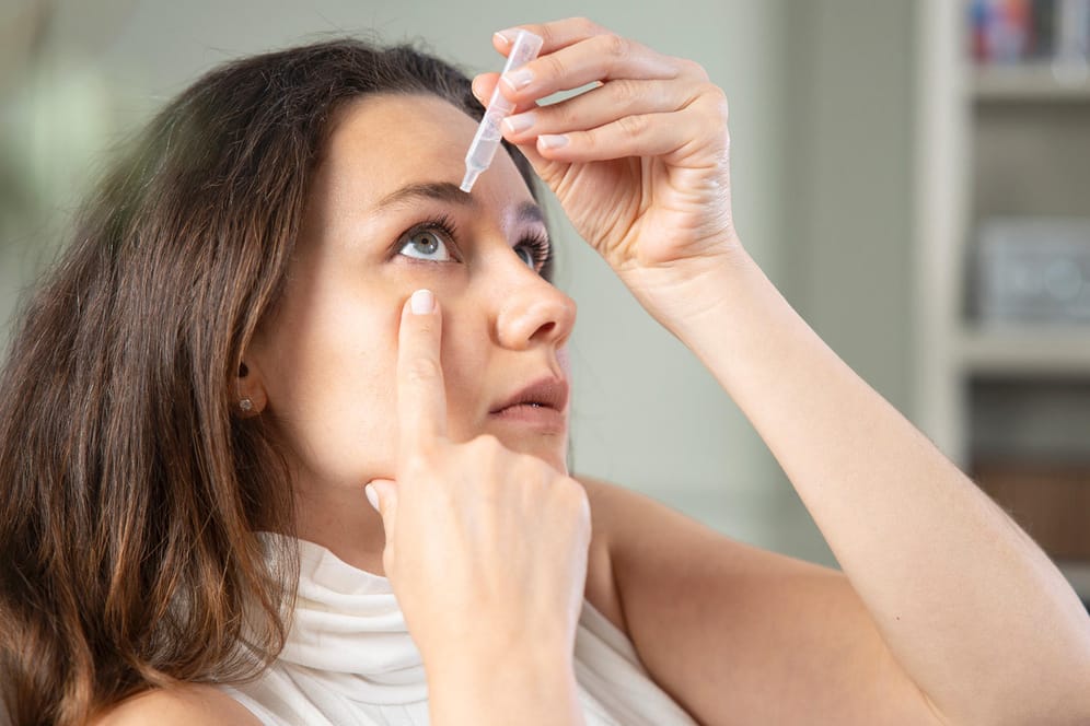 Frau nutzt Augentropfen: Wer zu trockenen Augen neigt, sollte für unterwegs immer ein paar Augentropfen zur Hand haben.