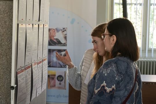 Frauen, die aus der Ukraine geflüchtet sind, informieren sich an einer Tafel über Arbeitsangebote.