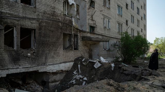 Eine Frau neben dem Krater einer Explosion, die in Lyman eine Wohnung und einen Keller eines Wohnhauses beschädigt hat.