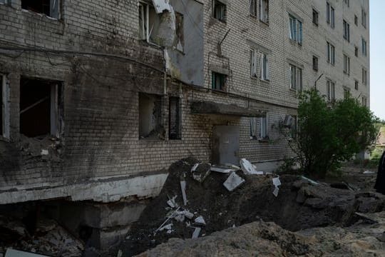 Eine Frau neben dem Krater einer Explosion, die in Lyman eine Wohnung und einen Keller eines Wohnhauses beschädigt hat.