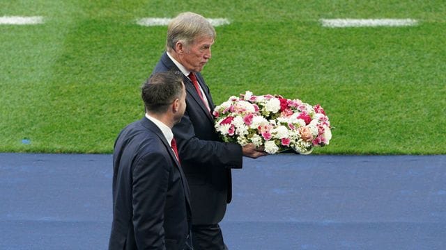 Liverpool-Legende Kenny Dalglish bringt den Kranz in Richtung eines hinter einem Tor angebrachten Vereinswappen der Reds.