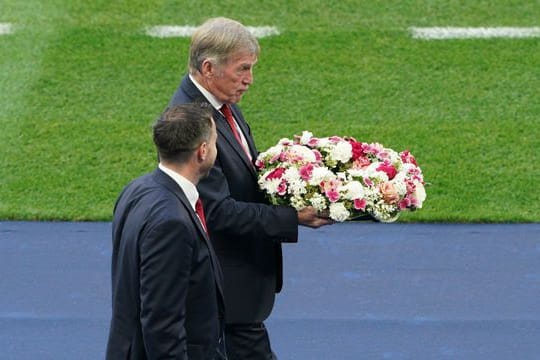 Liverpool-Legende Kenny Dalglish bringt den Kranz in Richtung eines hinter einem Tor angebrachten Vereinswappen der Reds.