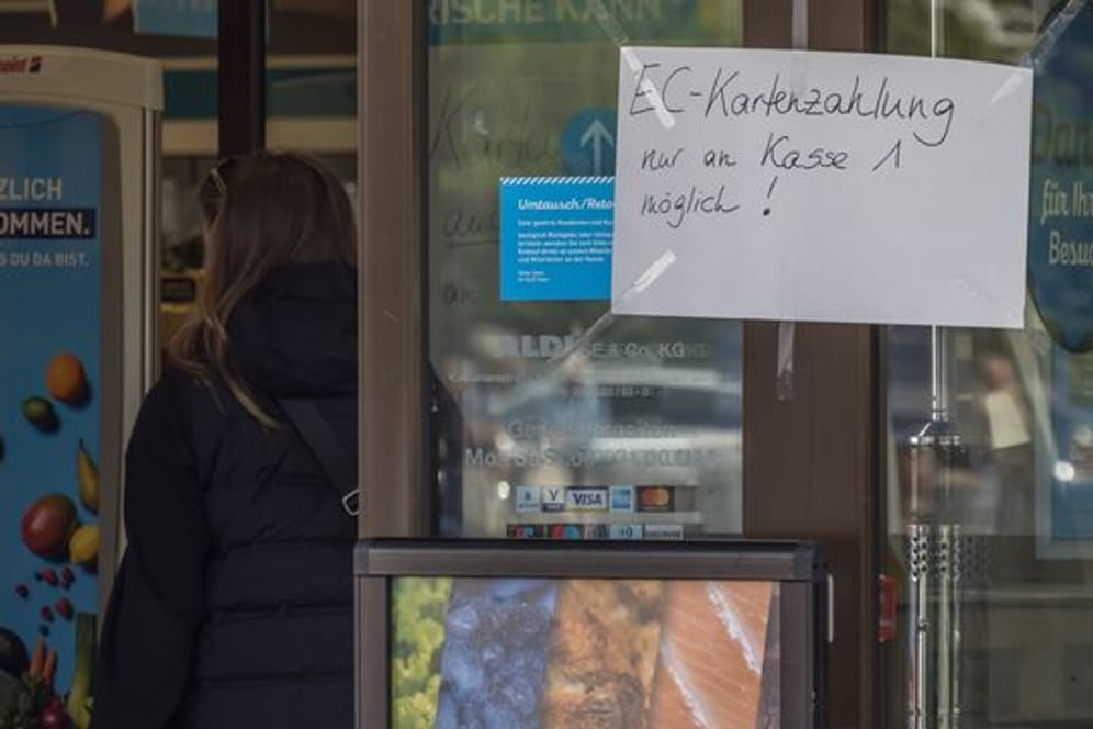 An der Eingangstür einer Filiale des Lebensmitteldiscounters Aldi Nord hängt ein handgeschriebener Zettel mit der Aufschrift "EC-Kartenzahlung nur an Kasse 1 möglich!".