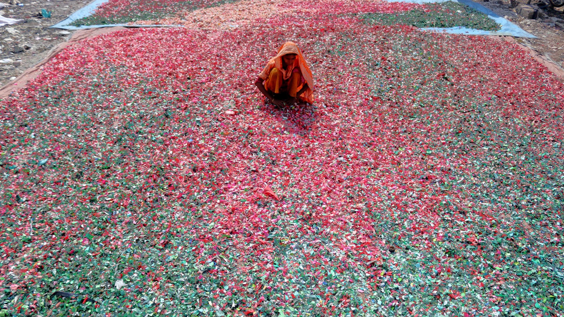 Eine Frau in Dhaka breitet gesäuberte und gehexelte Plastikchips zum Trocken aus: Coca-Cola hofft auf einen großen Umsatzzuwachs in dem Schwellenland. Das Plastikproblem ist dort bereits groß. Pfandsysteme gibt es nicht.