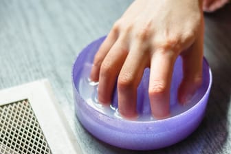 Eine Frau taucht ihre Finger in ein Handbad.