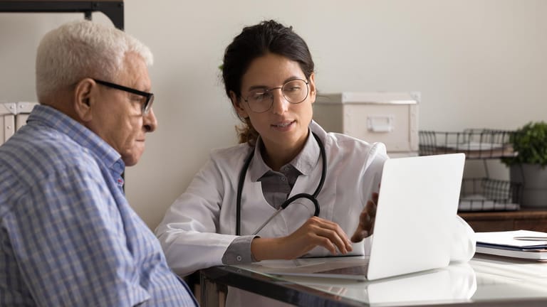 Eine Ärztin zeigt einem Patienten etwas auf einem Laptop.