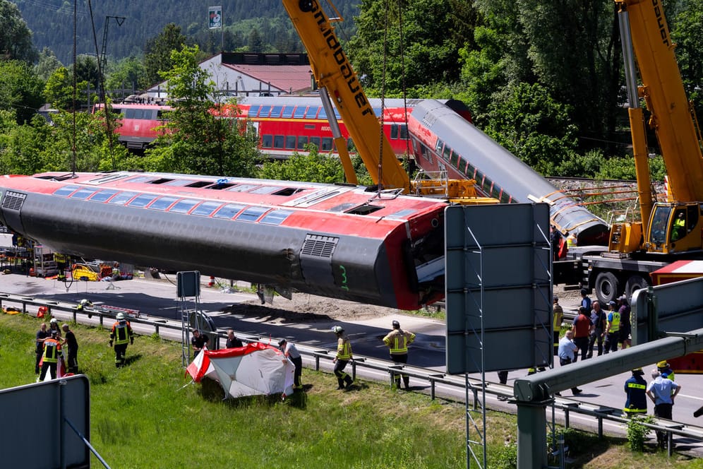 Rettungskräfte heben mit schwerem Gerät einen Wagen des Unglückszuges an: Unter dem Zug fanden die Helfer ein weiteres Todesopfer.