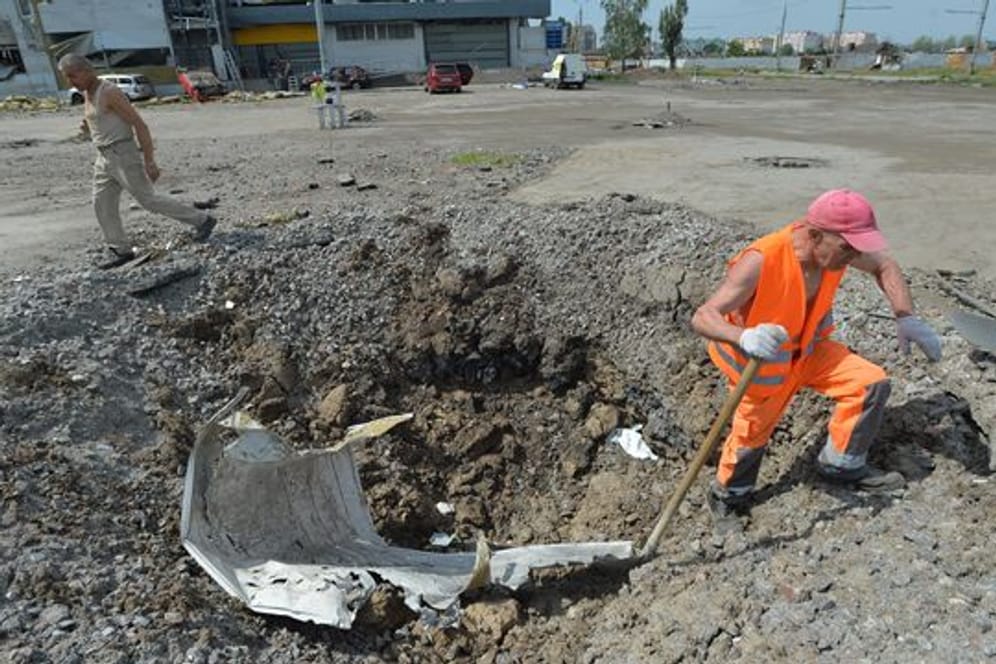 Ein Arbeiter beseitigt in Charkiw Rückstände aus einem Granatenkrater.