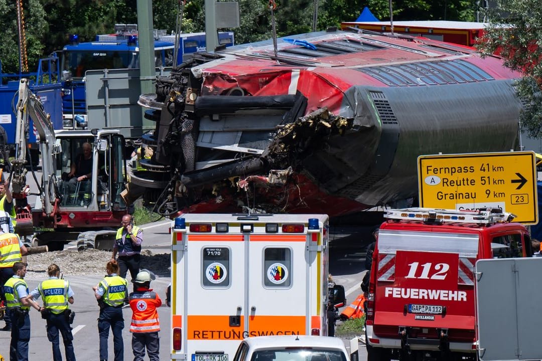 Die Rettungskräfte heben nach dem schweren Zugunglück einen der Waggons an.