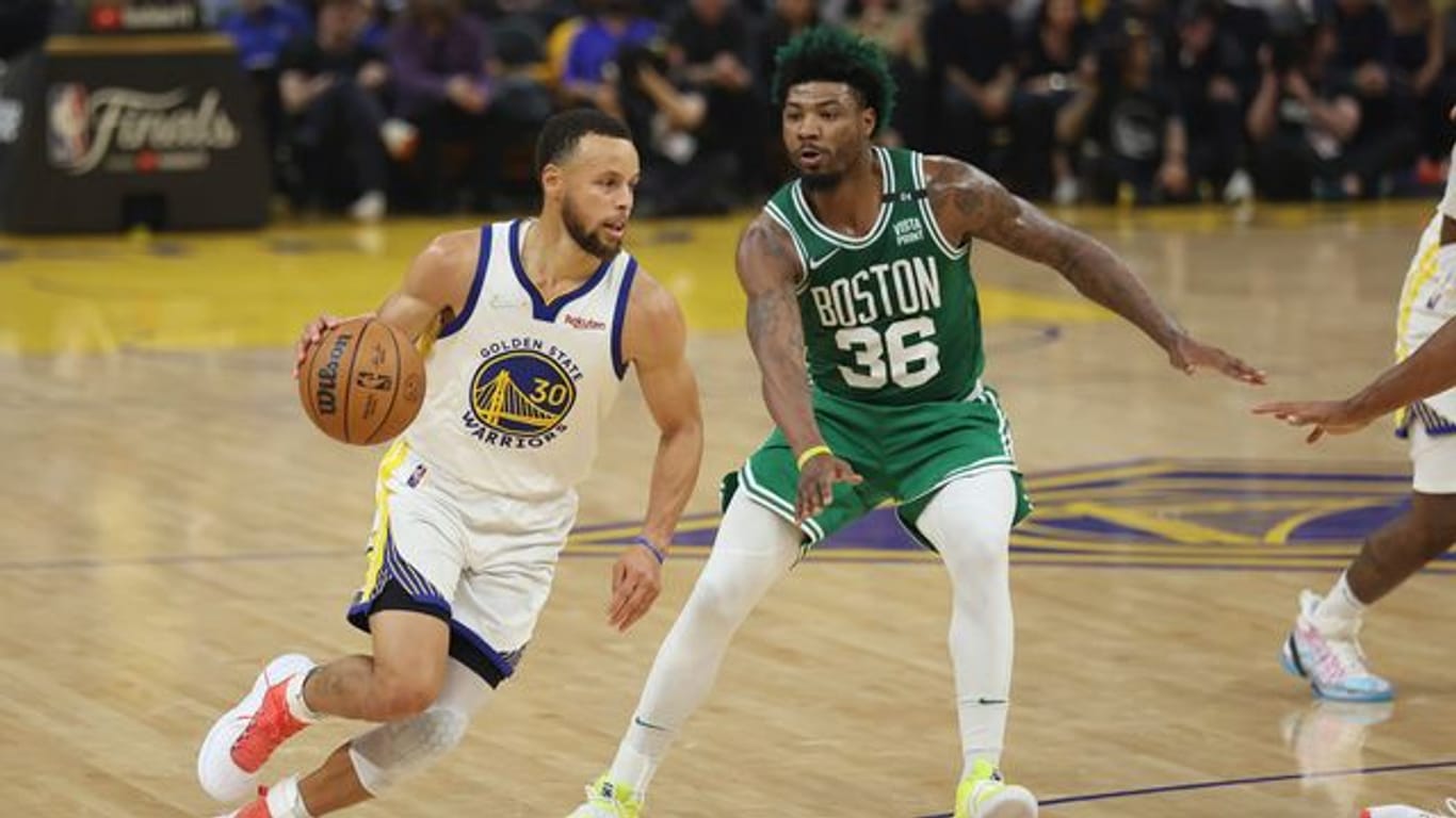 Stephen Curry (l), Guard der Golden State Warriors, zieht zum Korb gegen Marcus Smart, Guard der Boston Celtics.