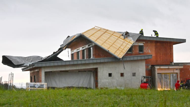 Österreich, Feldkirchen: Feuerwehrleute stehen auf einem Haus, dessen Dach von einem Sturm abgedeckt wurde.
