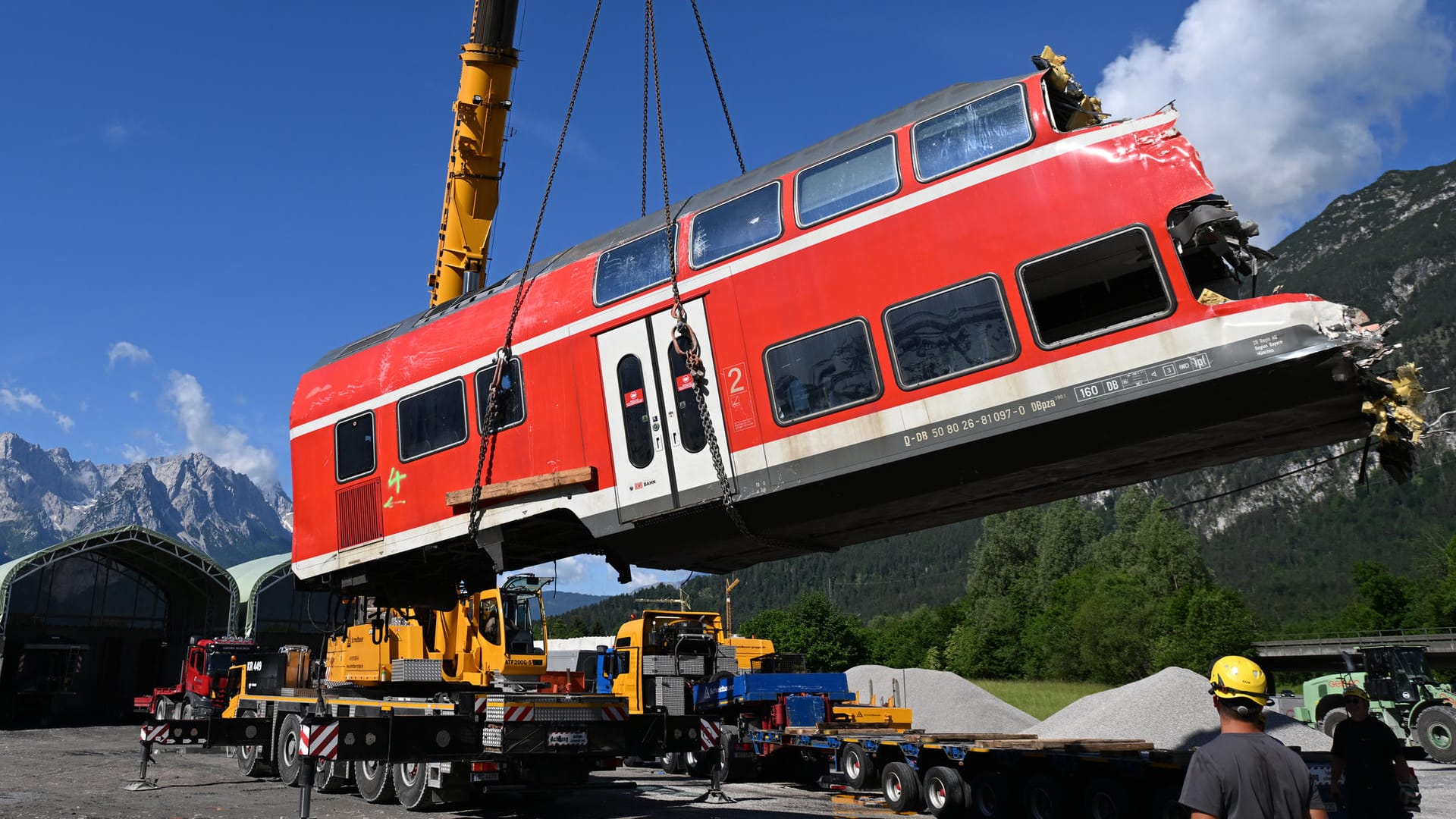 Ein auseinandergeschnittenes Waggonteil wird in einem nahe gelegenen Kieswerk vom Laster gehoben und gelagert.