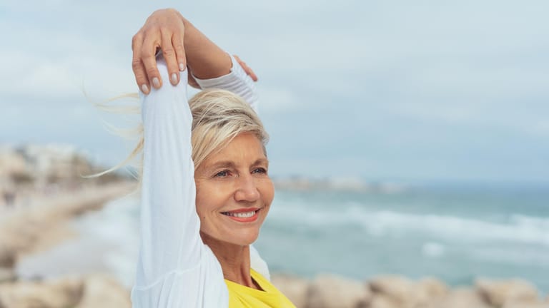 Glückliche ältere Dame am Meer. Wer einen gesunden Lebensstil pflegt, sich ausgewogen ernährt und körperlich aktiv bleibt, hat ein geringeres Risiko, im Alter an Alzheimer zu erkranken.