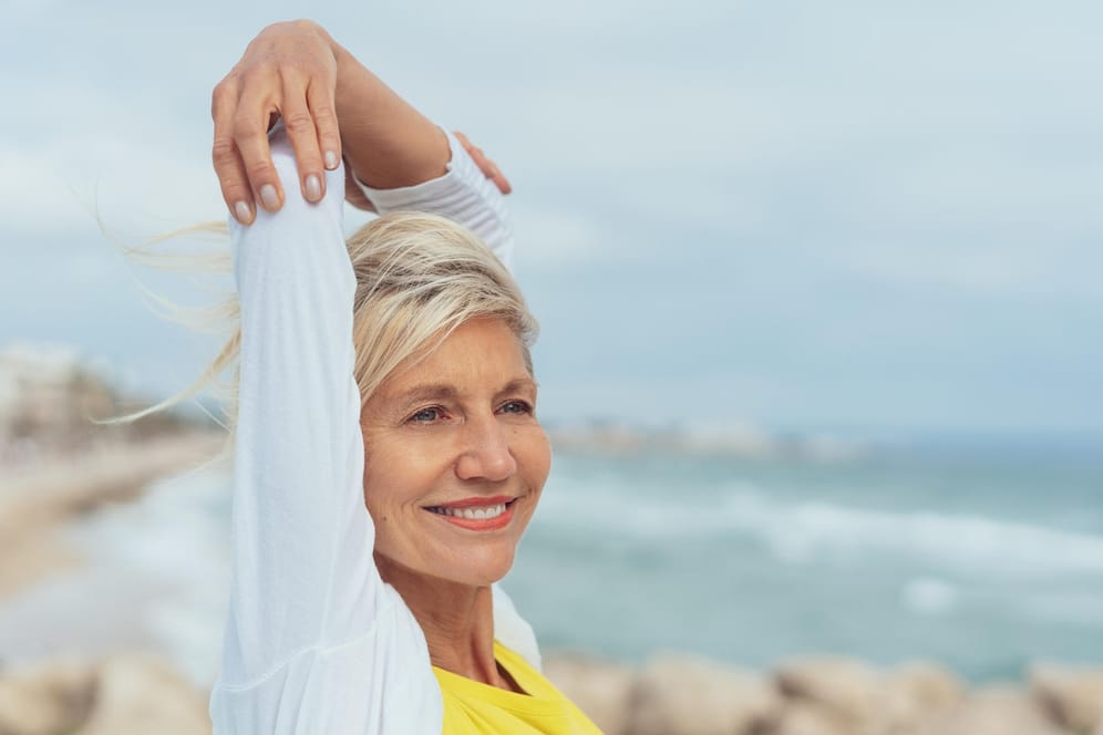 Glückliche ältere Dame am Meer. Wer einen gesunden Lebensstil pflegt, sich ausgewogen ernährt und körperlich aktiv bleibt, hat ein geringeres Risiko, im Alter an Alzheimer zu erkranken.