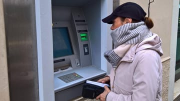 Frau hebt Geld ab: Durch die Inflation verliert das Geld an Wert.