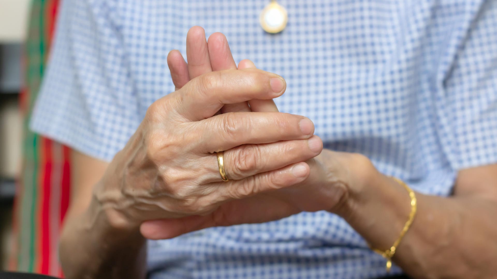 Eine Frau hält die Finger ihrer linken Hand umschlossen.