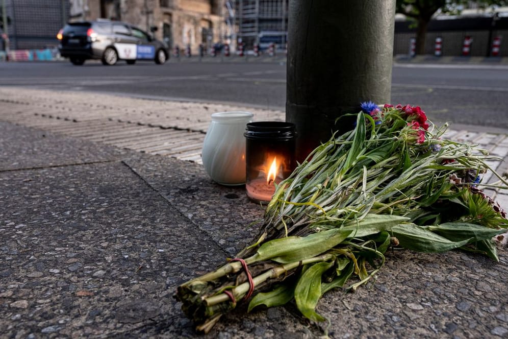 Kerzen und ein Blumenstrauß liegen zum Gedenken auf dem Bürgersteig an der Tauentzienstraße in Berlin.
