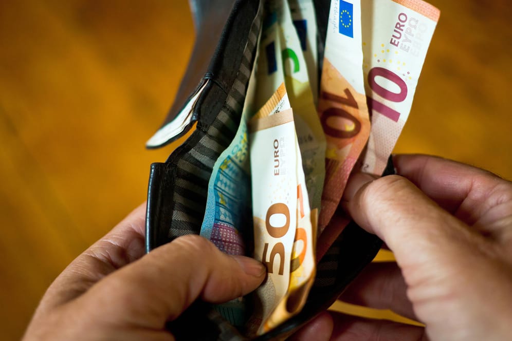 Eine Person nimmt Geld aus einem Portmonnaie (Symbolbild): Die Zinsentscheidung der EZB wirkt sich auch auf Sparer aus.