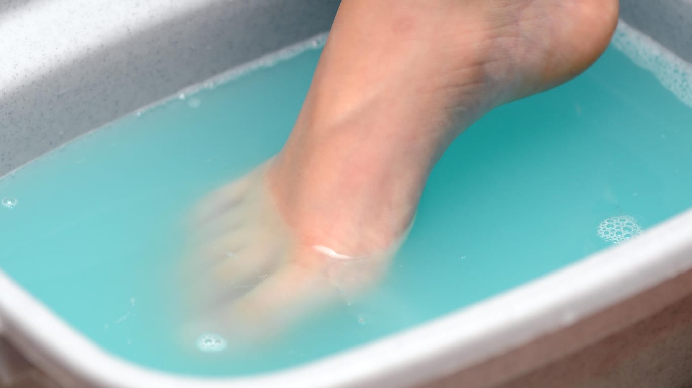 Eine Frau taucht einen Fuß in ein Fußbad.