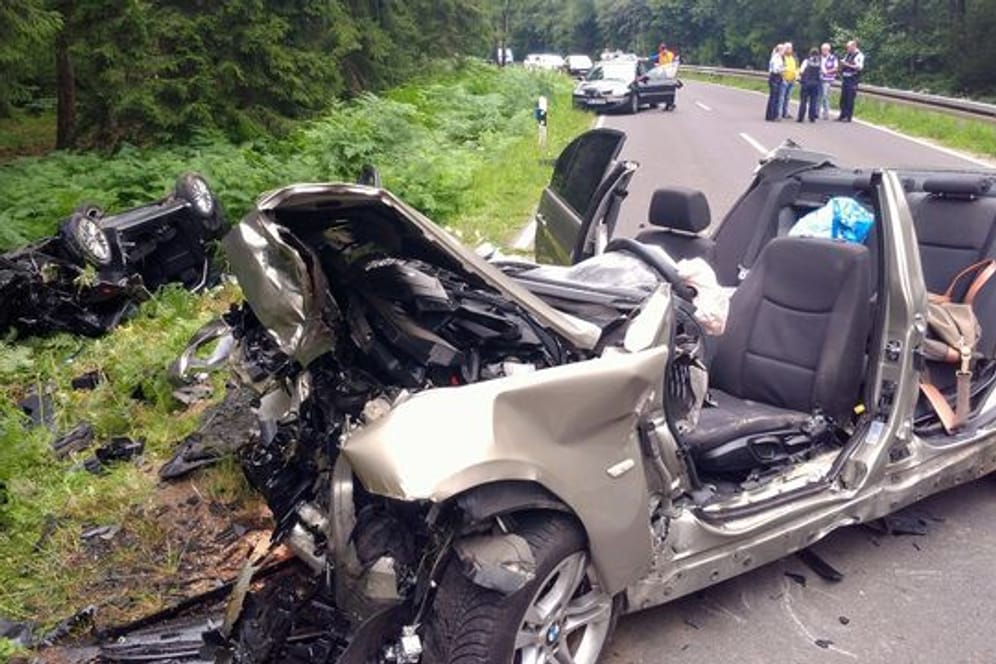 Zwei vollkommen zerstörte Autos liegen nach dem Unfall am Rand der Landstraße L12 zwischen Roetgen und Simmerath in der Eifel.