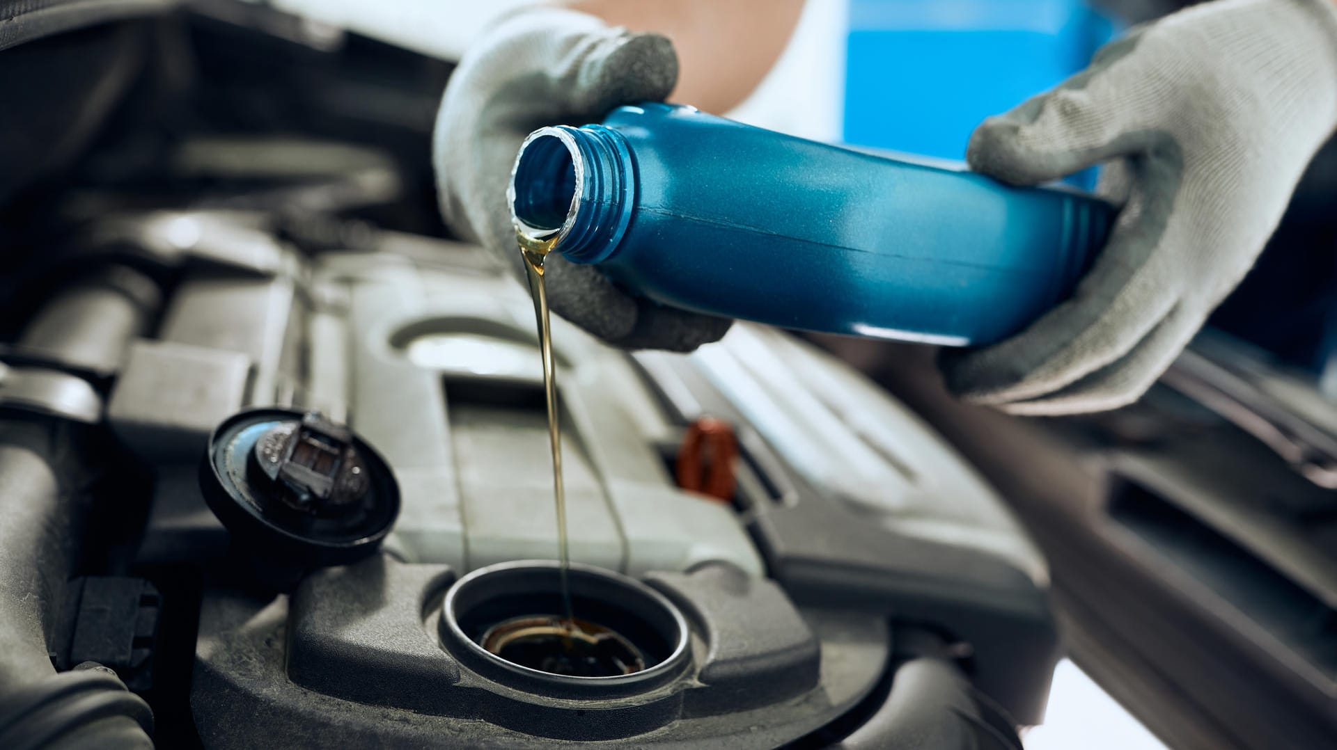 Close-up of repairman changing engine oil while working at car workshop.
