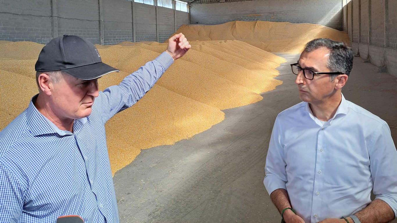 Landwirtschaftsminister Cem Özdemir besichtigt mit Landwirt Viktor Scheremeta eine Halle in Jerkiwzi, in der Mais gelagert wird.