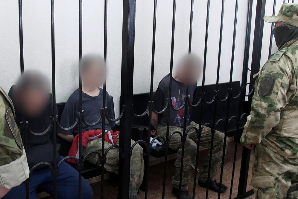 Die beiden britischen Staatsbürger (links und rechts) und der marokkanische Staatsbürger in einem Gerichtssaal in Donezk: Am Donnerstag wurden sie zum Tode verurteilt.